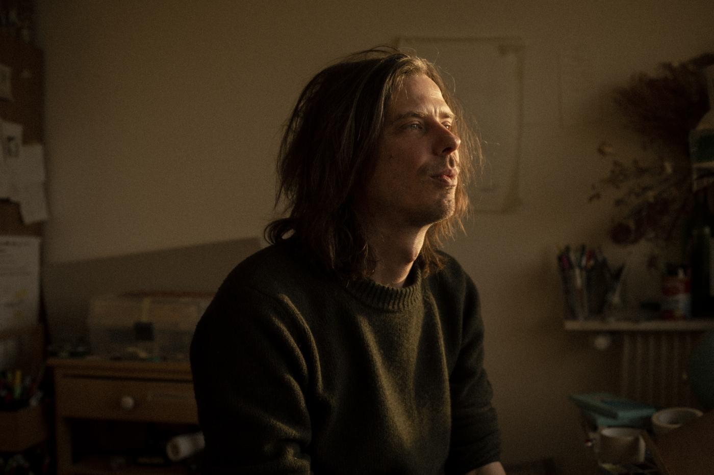 Portretfoto van auteur Brecht Evens in een donkere ruimte waarbij er licht op zijn gezicht valt