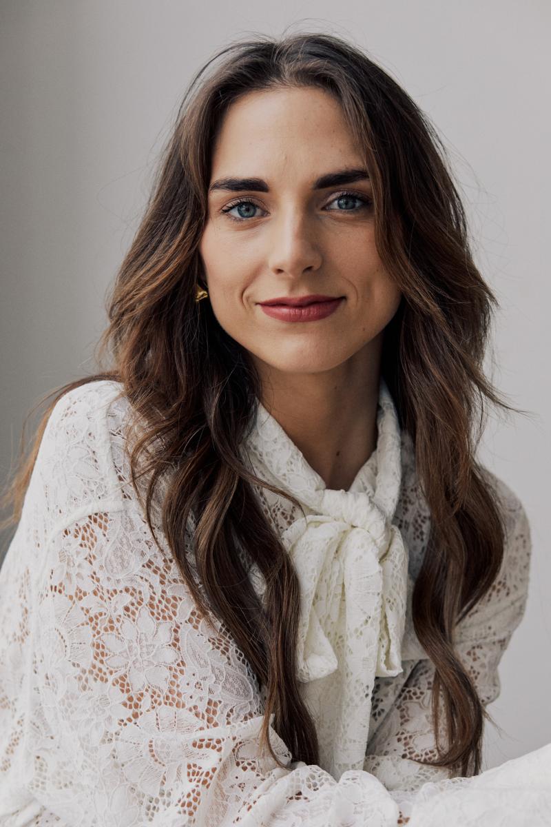 Auteur Elisabeth Lucie Baeten, vrouw met lang donker haar en witte trui