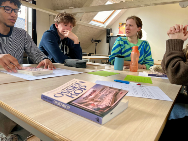 Leerlingen aan een tafel in de klas, in de voorgrond het boek 'Ossenkop' van Manik Sarkar